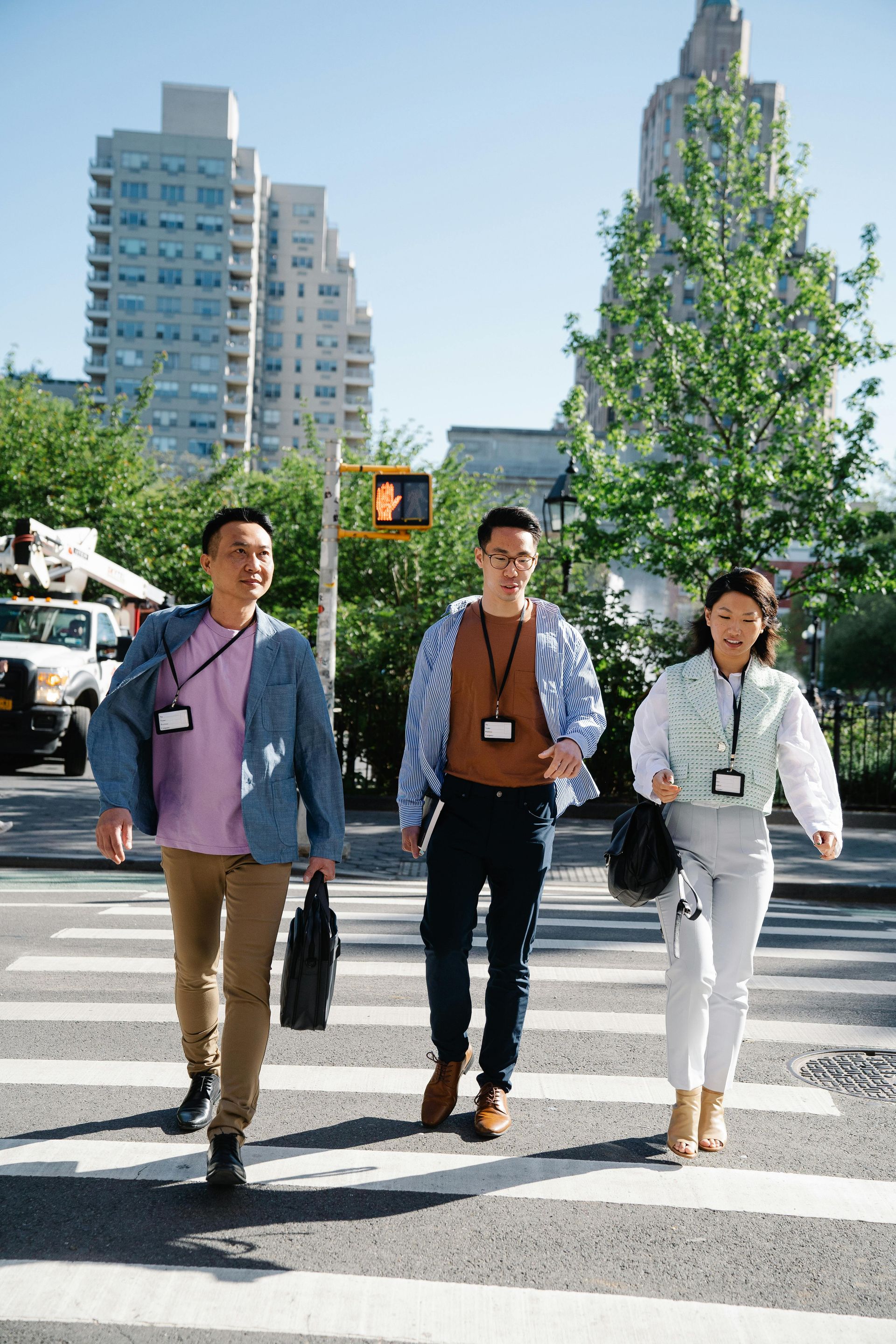 Three professional colleagues walking across a city street during a sunny day.